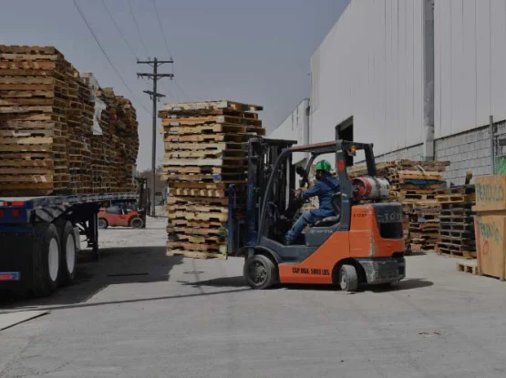 Montacargas operado por un trabajador de KAYAK Packaging subiendo tarimas de madera a un camión.