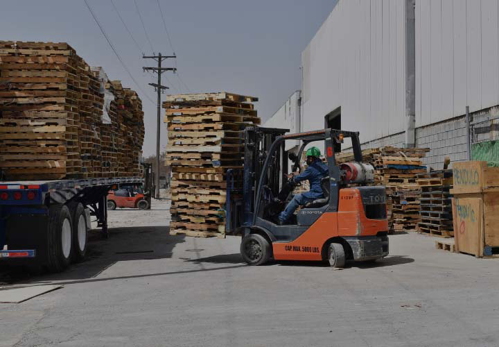 Montacargas operado por un trabajador de KAYAK Packaging subiendo tarimas de madera a un camión.